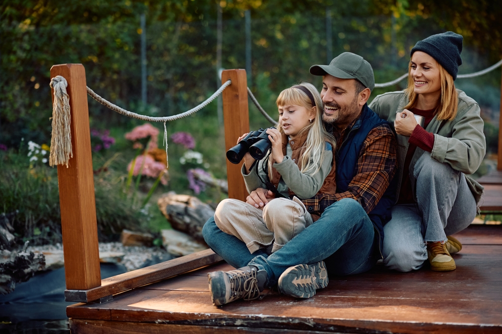 Family of four sitting together on a wooden footbridge in a garden