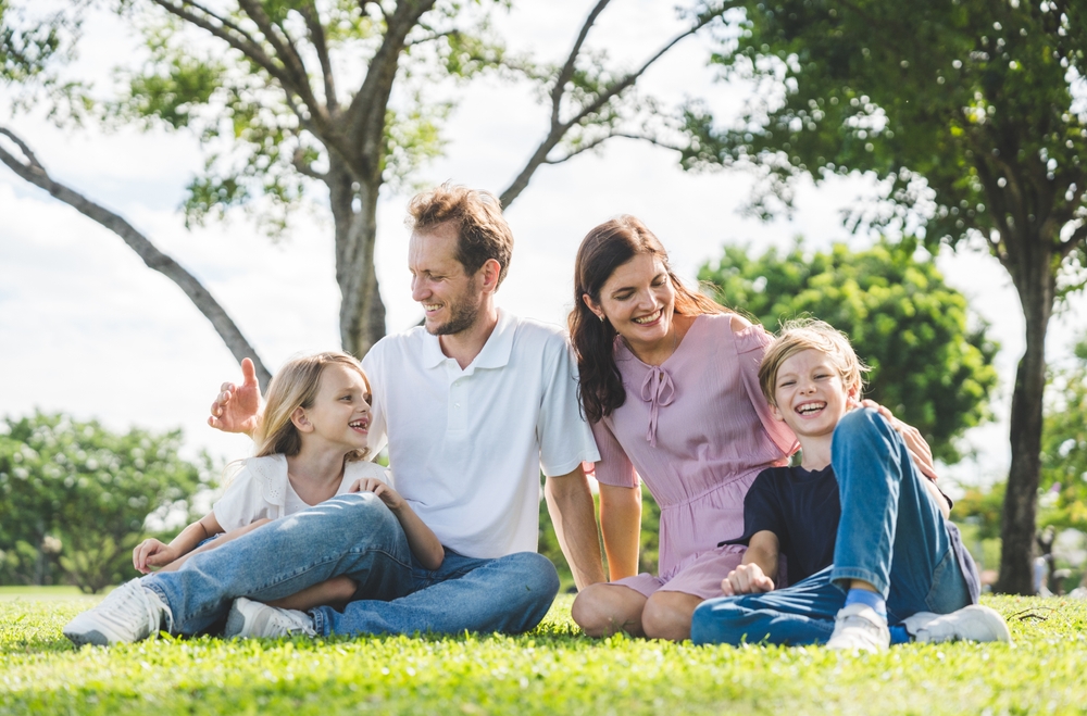 Family of four relaxing together on the grass in a park