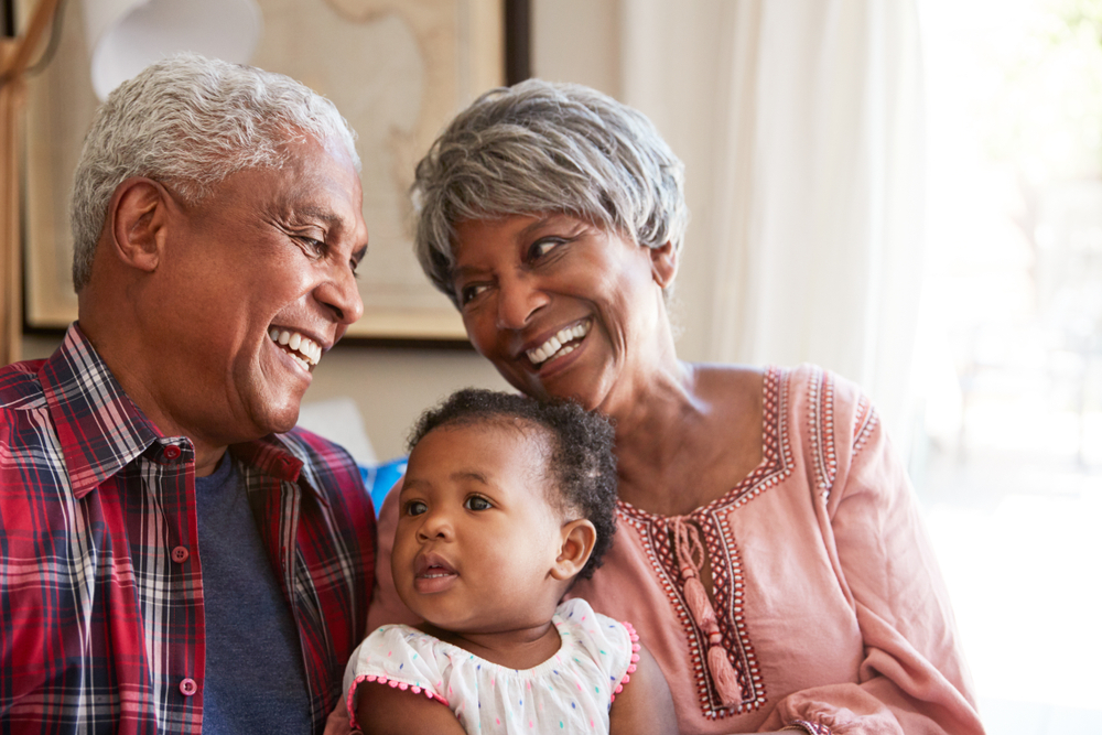 Smiling grandparents holding their baby granddaughter