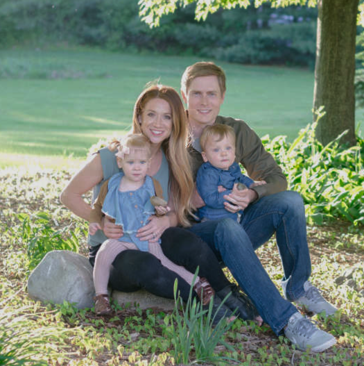 Dr. Brian Hill with his wife and children, sitting together on the grass outdoors